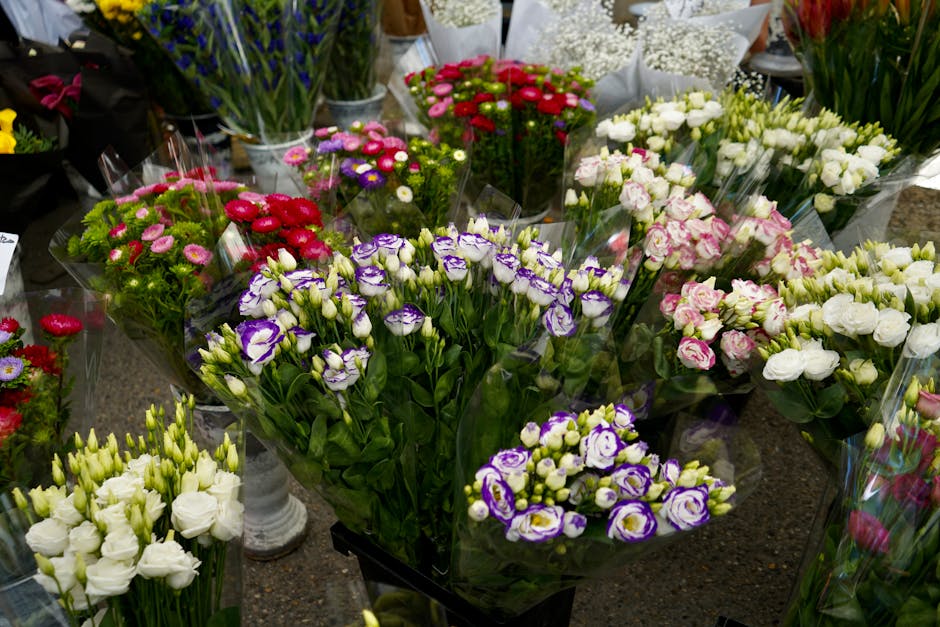 An assortment of fresh floral bouquets displayed on a shop counter, featuring a variety of flowers including purple and white lisianthus, pink and white carnations, white roses, and small daisy-like b