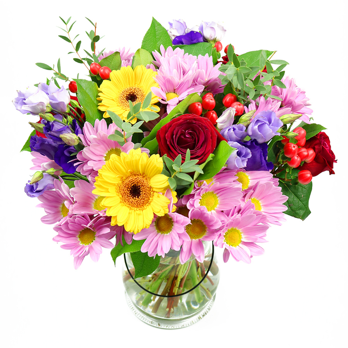 A vibrant mixed bouquet in a cylindrical glass vase is showcased against a crisp white background, every bloom standing out clearly as if arranged on a sunlit table in a Thames Ditton townhouse. The centre of the arrangement is anchored by plush, deep red roses, their layered petals unfolding in rich, romantic spirals. Nestled beside them, two radiant yellow gerbera daisies with dark, warm-toned centres create a vivid contrast, their flat, open faces suggesting laughter and celebration. Surrounding this bold core, generous clusters of pink and soft lavender daisies or chrysanthemums fill the bouquet, their many fine petals and tiny yellow centres giving a sense of abundance and gentle, comforting colour, like a cottage garden in full bloom near Ember Court Road. Threaded among the daisies are elegant lisianthus stems in purple and pale lilac, their bell-shaped flowers and tender buds adding height, movement, and a cool, sophisticated undertone that balances the warmer hues. Bright red hypericum berries pop up between the petals, round and polished, adding playful texture and an almost festive character without overpowering the design. Lush greenery weaves throughout the bouquet: glossy dark leaves provide structure and depth, while lighter, more feathery sprigs soften the edges and bring a sense of natural, airy freshness. Through the transparent vase you can see the neatly gathered stems, trimmed to a clean line and immersed in clear water, reflecting the careful craftsmanship of a seasoned florist. This arrangement feels ideal for marking happy milestones in Thames Ditton-from birthday gatherings off Station Road to heartfelt thank-you gifts-bringing colour, fragrance, and a quietly joyful presence into any room.